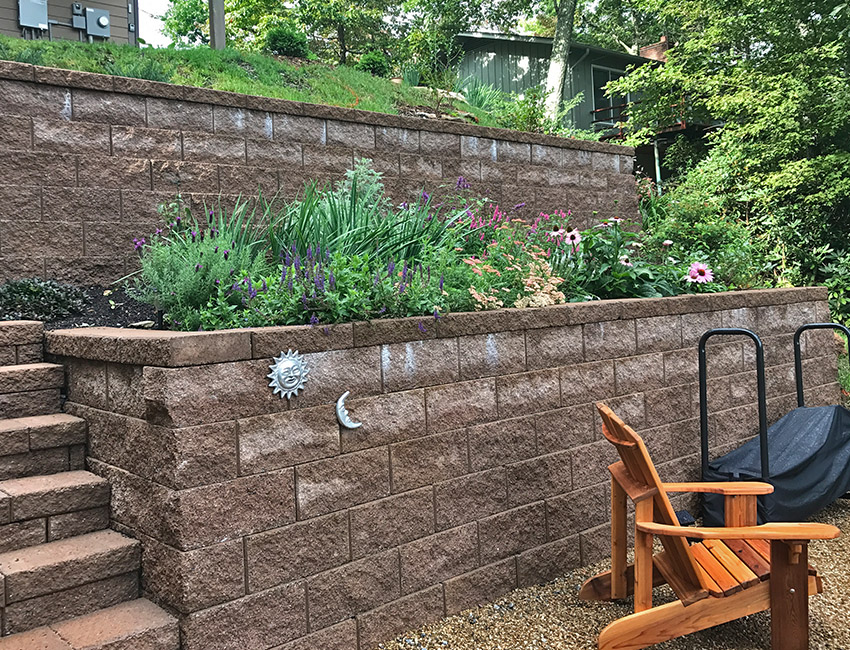 A brick retaining wall with a lawn chair next to it.