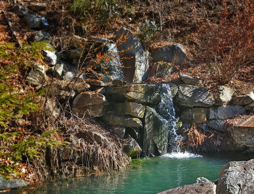 A small waterfall surrounded by rocks in a wooded area.
