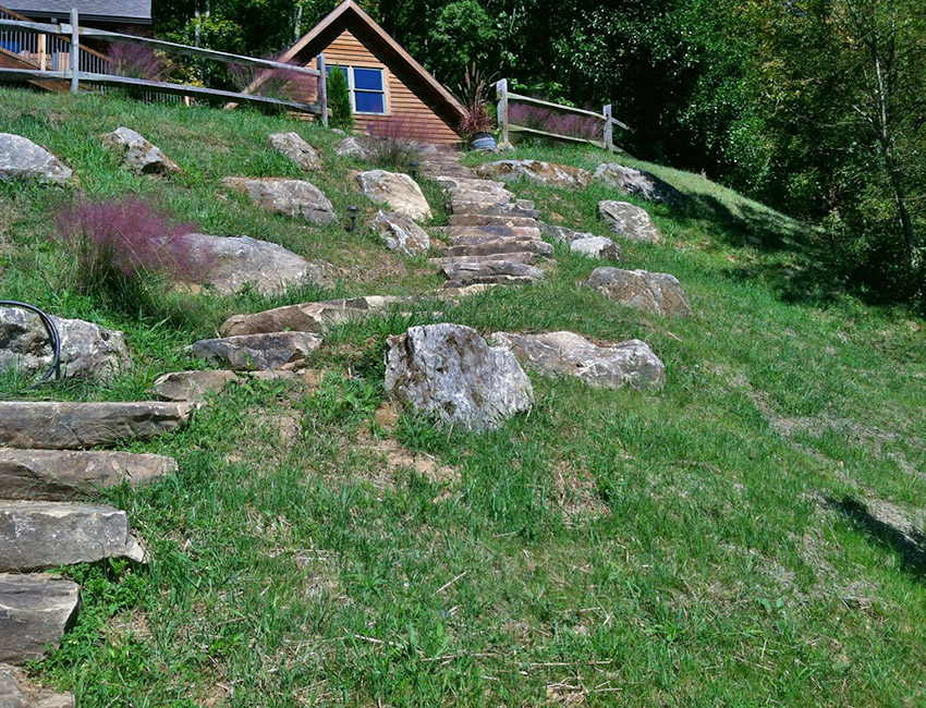 A grassy hill with steps leading to a house.