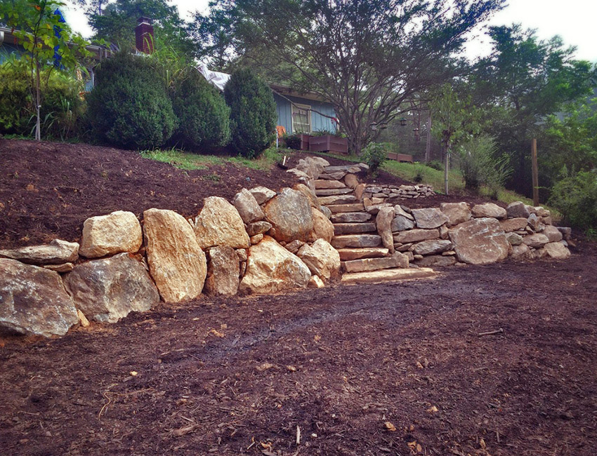 A stone wall with steps leading up to a house.