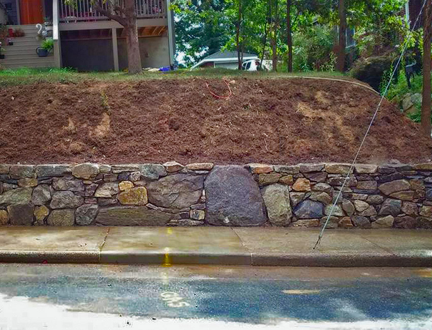A stone wall is being built in front of a house.