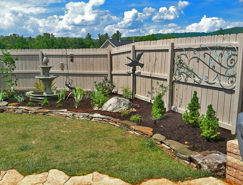 A backyard with a fence and a fountain.