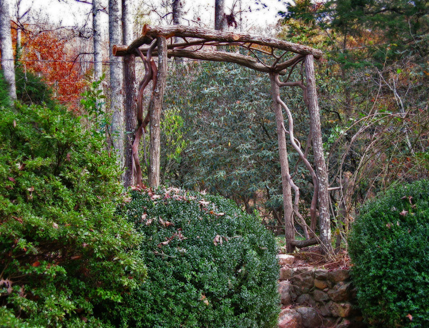A wooden archway in the middle of a wooded area.