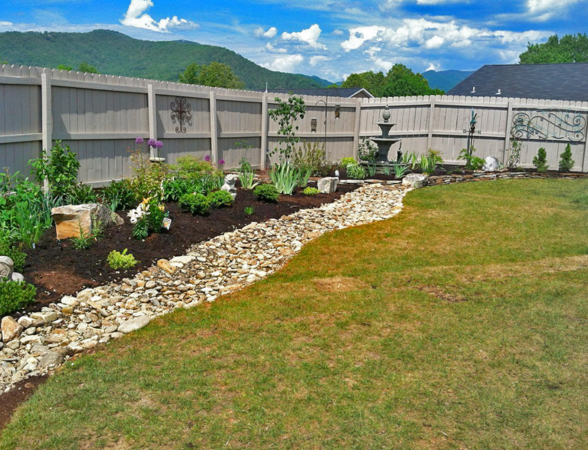 A backyard with a rock garden and a fence.