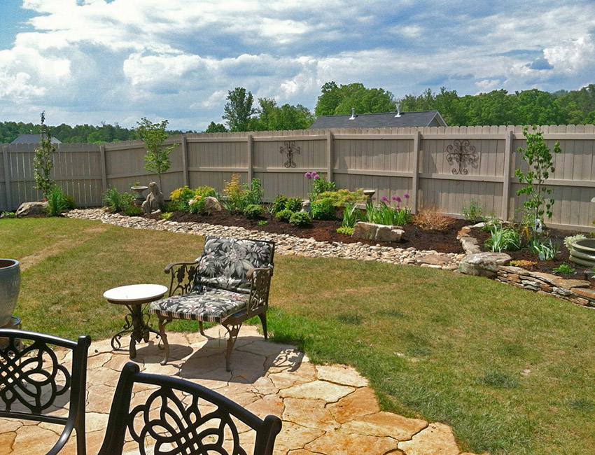 A backyard with a fence and a table and chairs.