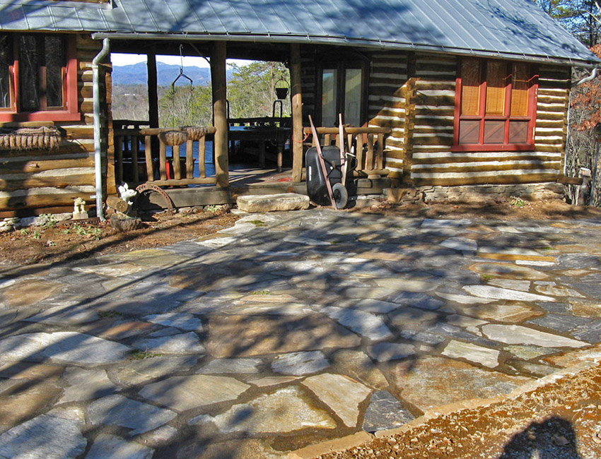 A stone patio in front of a log cabin.