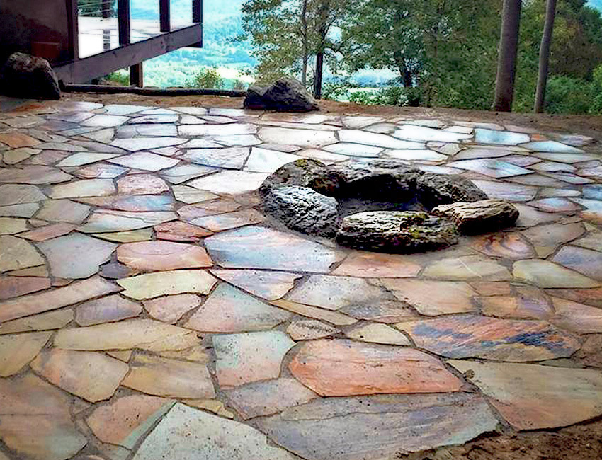 A stone patio with a fire pit in the middle.