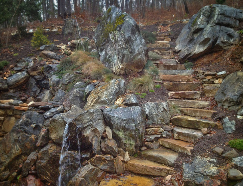A stairway leading to a waterfall in a wooded area.