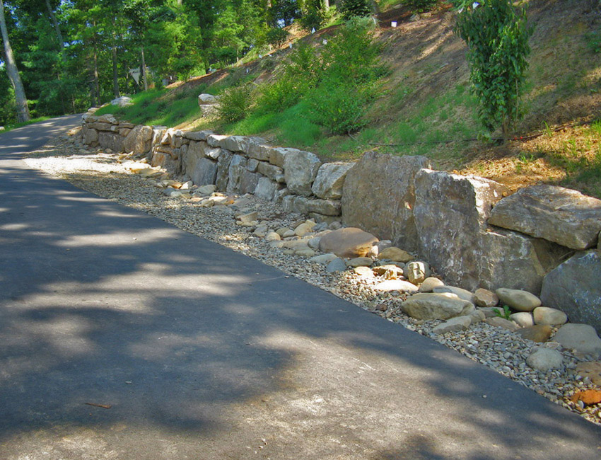 A stone wall next to a road.