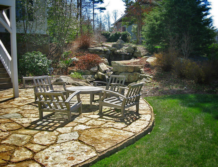 A stone patio with a table and chairs.